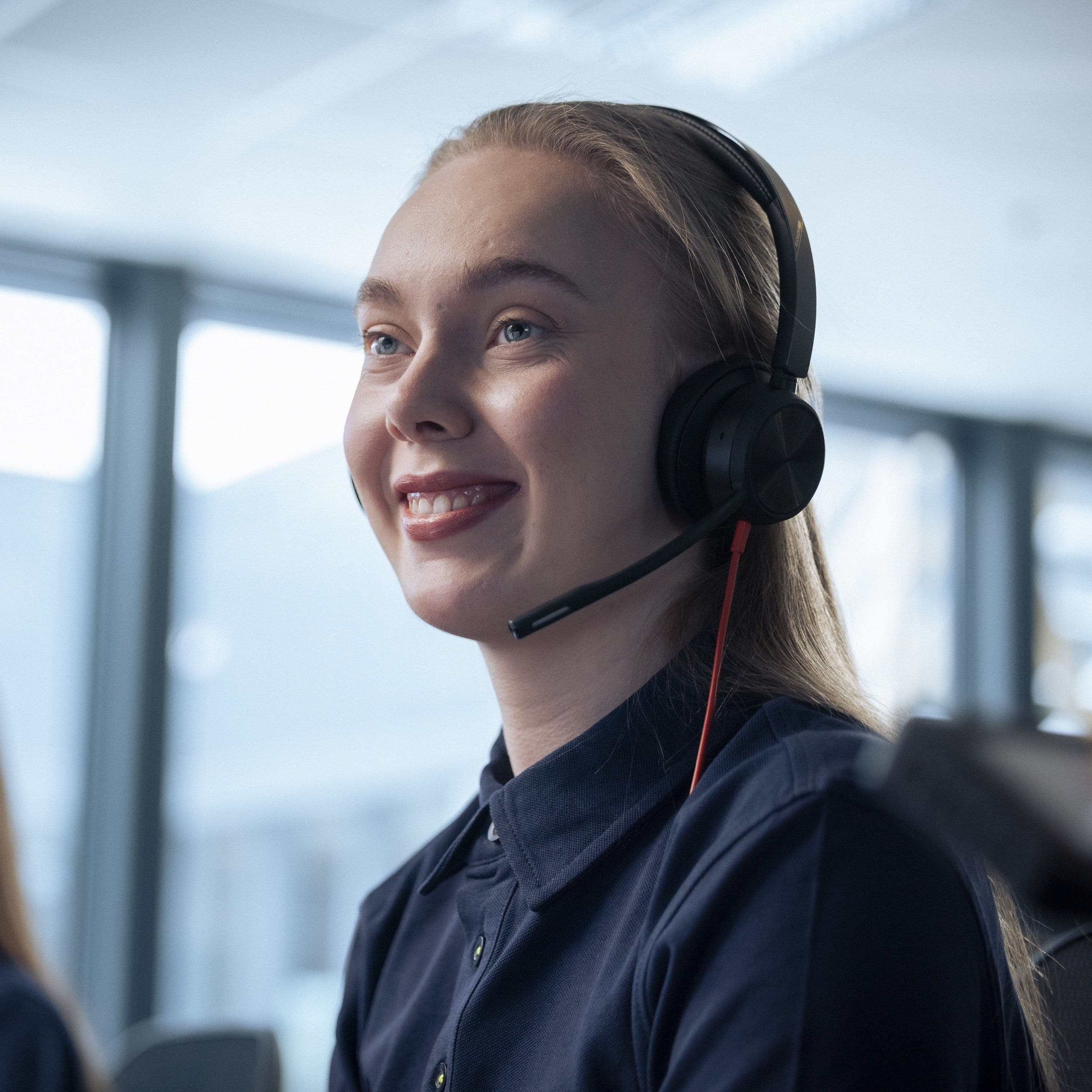 Close-up of a smiling woman wearing a headset with a microphone.